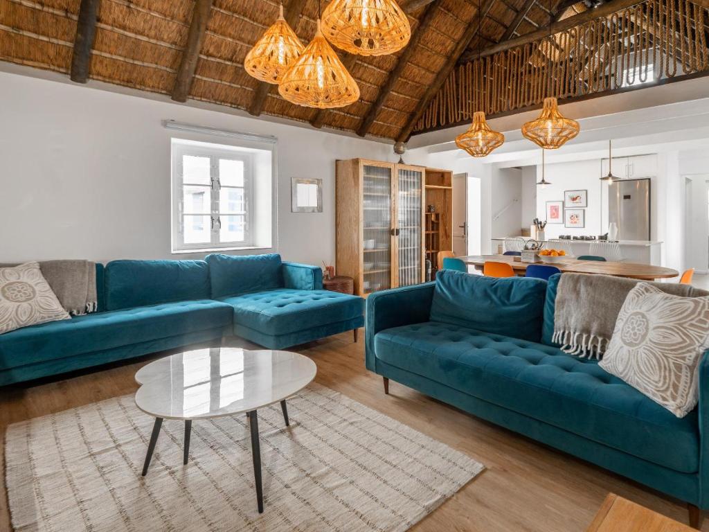 a living room with blue couches and a table at 4131 Beach Drive Bliss & Flip Flop Cottage in Struisbaai