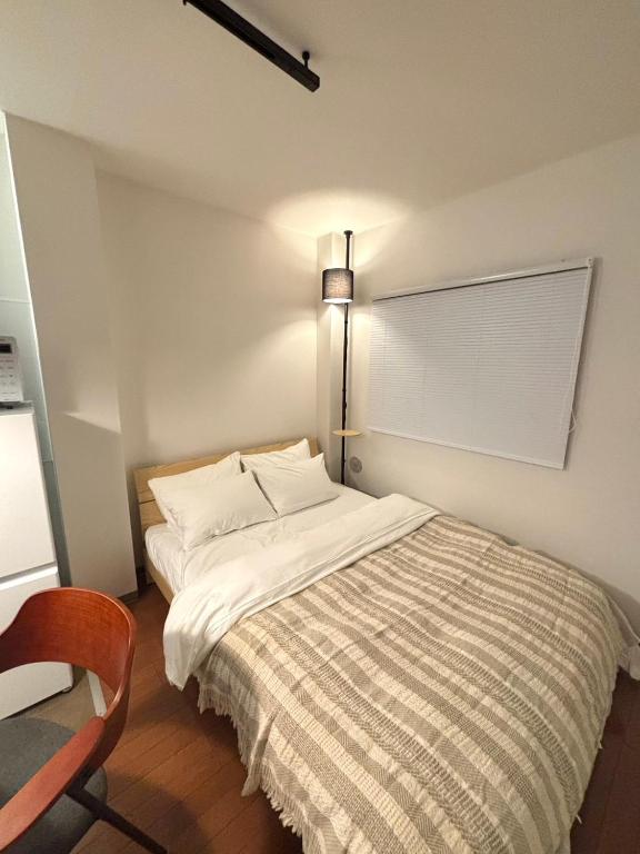 a bedroom with a bed and a chair and a lamp at 大泉学園 練馬の家灯 池袋まで15分 としまえん 吉祥寺 飯能 観光に in Yagisawa