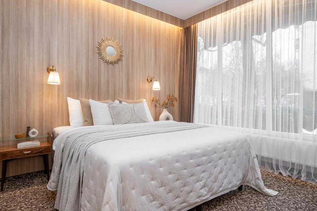 een slaapkamer met een groot wit bed en een raam bij Nėris Inn Terraces in Vilnius