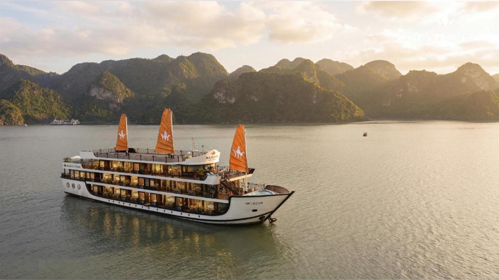 a cruise ship in the water with mountains in the background at Majesty Luxury Prime Cruise by Premier Group in Ha Long