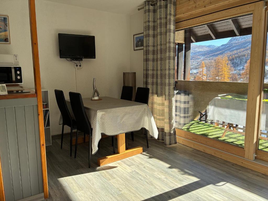 a dining room with a table and chairs and a window at Parc des Ecrins 05290 Les MAISONNETTES APPARTEMENT 4 Pers in Puy-Saint-Vincent