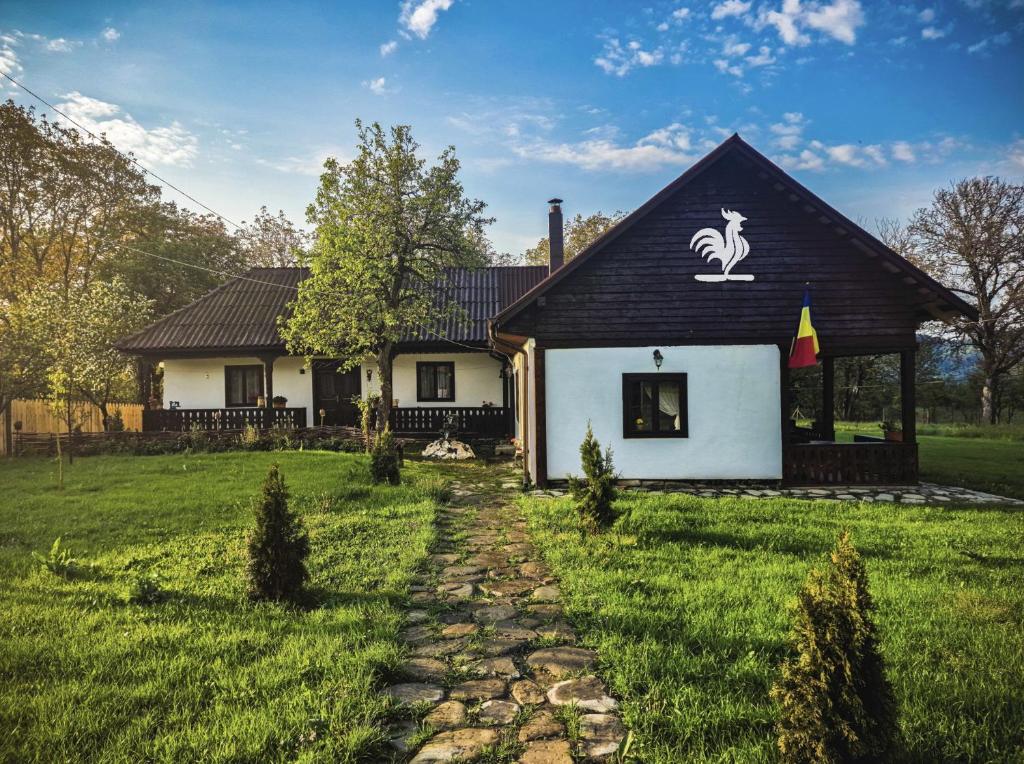 a small white house with a black roof at Pensiunea Cocoș in Spulber
