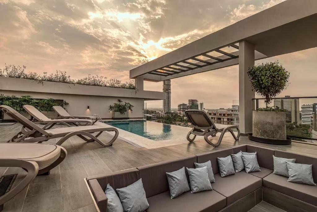 Un patio en la azotea con un sofá y sillas y una piscina. en Zuba IV, en Luque