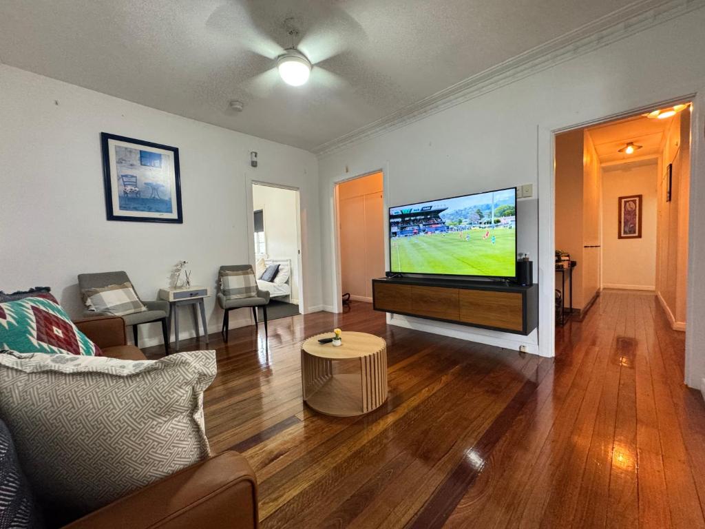 Cosy Cottage 4173 في بريزبين: غرفة معيشة مع تلفزيون بشاشة مسطحة وأريكة