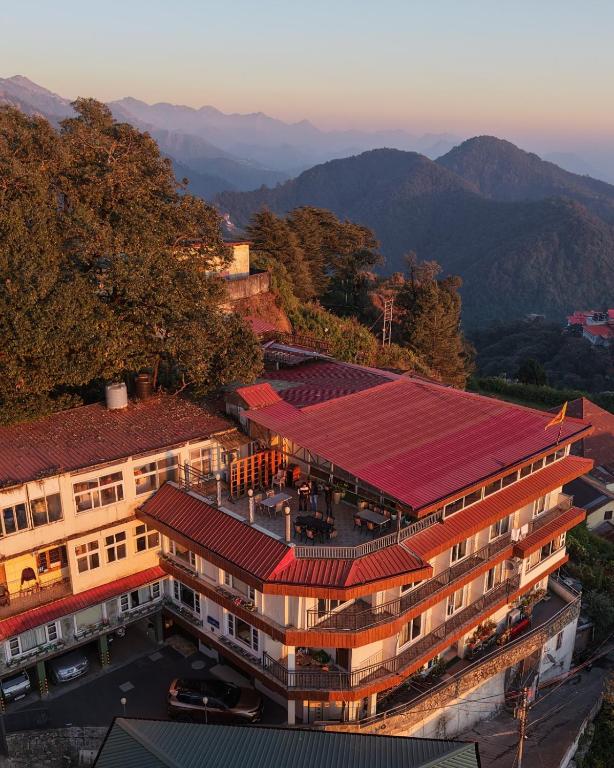 a building with a red roof with mountains in the background at Vaydantaa - Luxury Boutique Hotel Mussoorie in Mussoorie