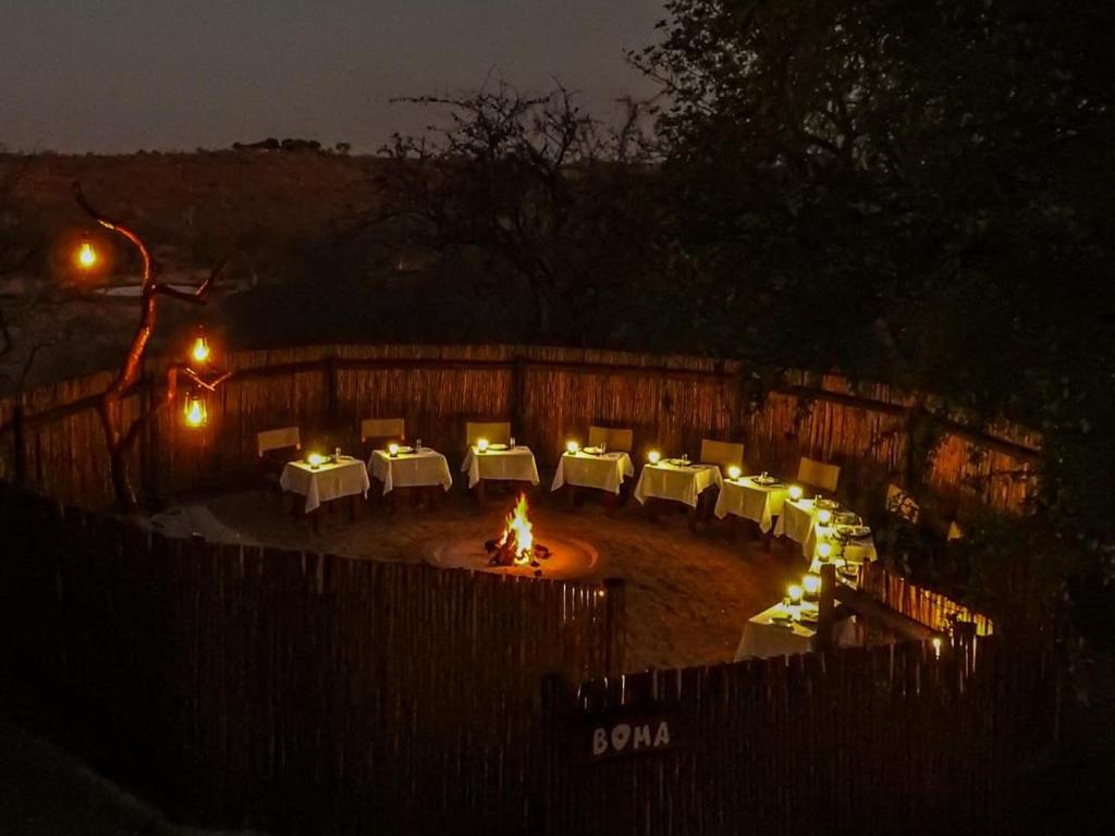 a group of tables and chairs in a yard at night at Mazuri Shamba Lodge in Phalaborwa