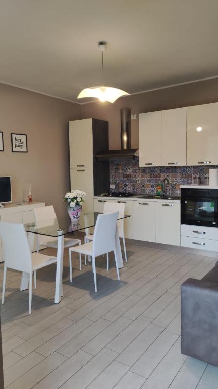 DelloDello Home的配有白色橱柜、桌子和椅子的厨房