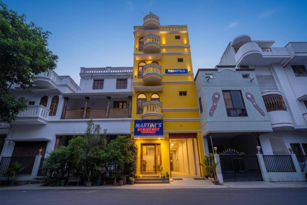 a yellow building with a clock tower in the middle at FabHotel Martine's Residency - French Colony, 5 Mins from Rock Beach in Puducherry