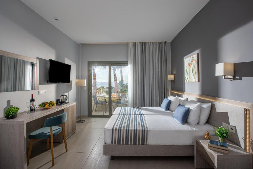 a bedroom with a bed and a desk and a television at Saint George Gournes Bay "by Checkin" Adults Only in Gournes