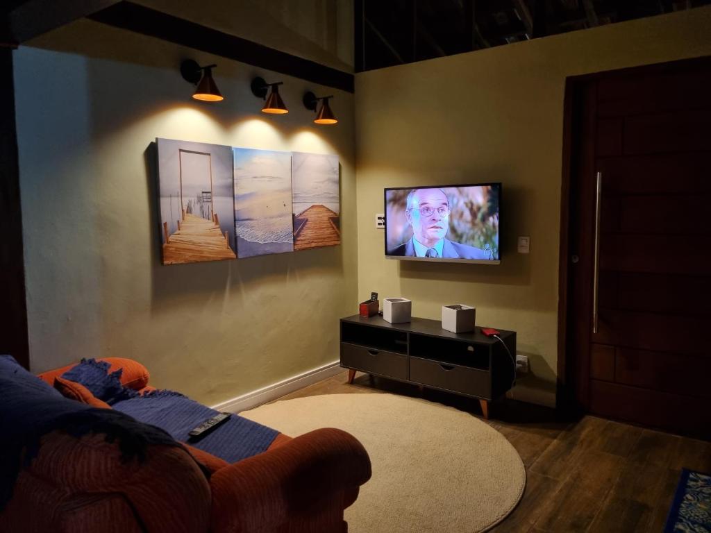 a living room with a tv on a wall at CASA em CAMBURI in São Sebastião