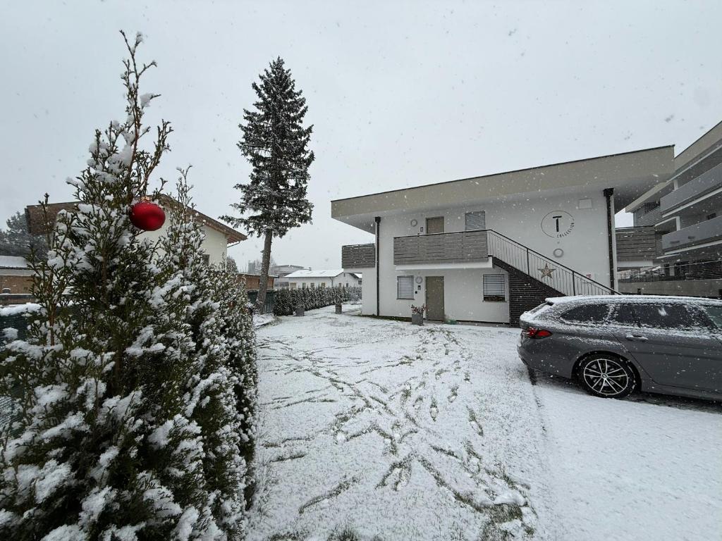 a snow covered yard with a christmas tree and a car at T-Collection Premium Apartments in Vipiteno