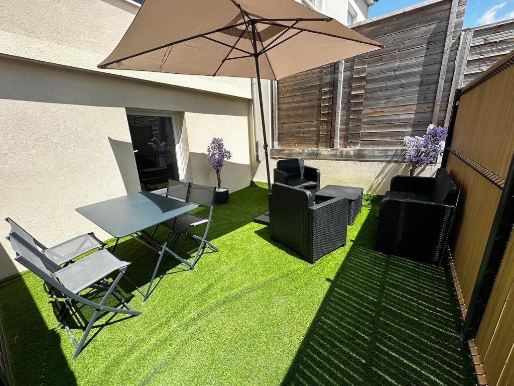 eine Terrasse mit Tisch, Stühlen und Sonnenschirm in der Unterkunft F2, near Disney in Guérard