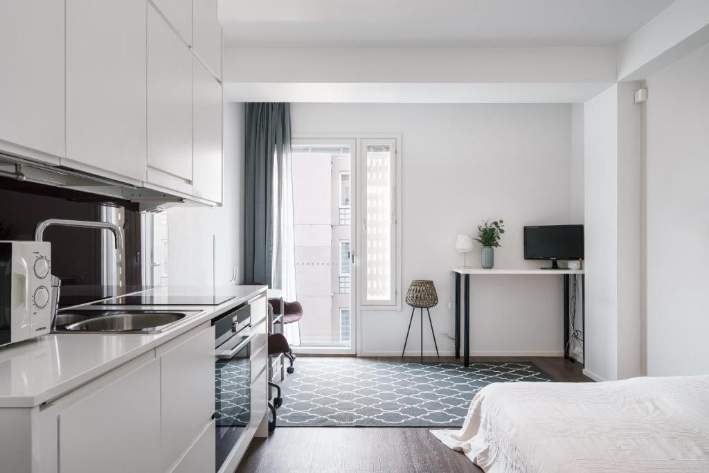 a kitchen with white cabinets and a bed in a room at Modern Studio Apt in Design District in Helsinki