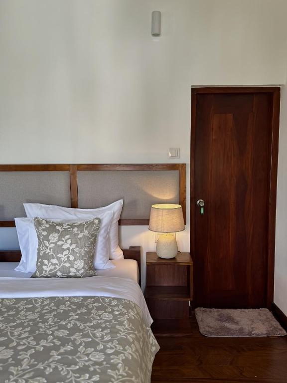 a bedroom with a bed and a lamp and a door at Luxe Hideaway in Colombo