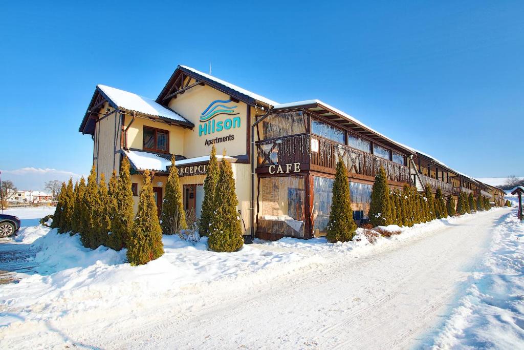 a large building with trees in the snow at Hilson Jasna - Garden resort in Liptovský Mikuláš