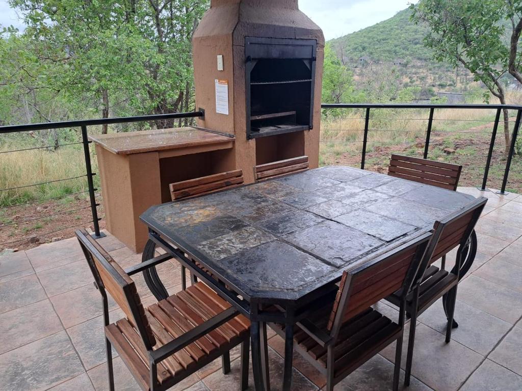 Unit 77 Kubu Mabalingwe nature reserve في وارمباثس: طاولة وكراسي على فناء مع شواية