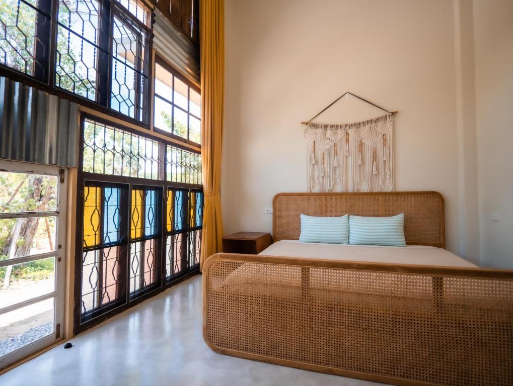 a bedroom with a bed and large windows at Baan Mahasamut Pranburi in Sam Roi Yot