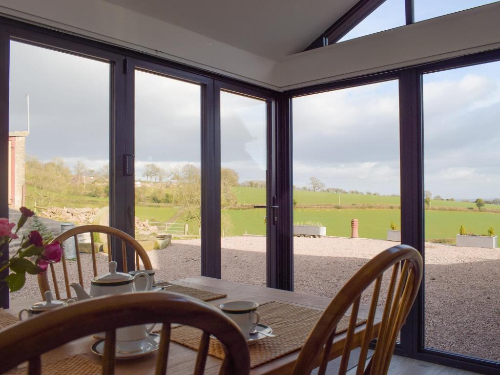 a dining room with a table and chairs and windows at Cider Mill in Bullingham