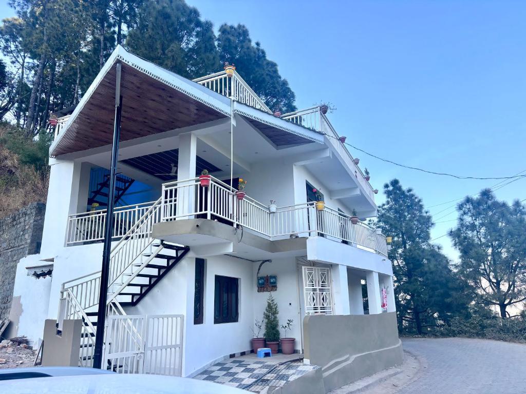 a white house with stairs and a balcony at The Glades 2BHK kasauli in Kasauli