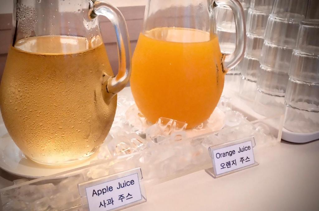 two pitchers of orange juice on a table with price signs at INSOMNIA Hotel in Hyomoktong-Ilgu