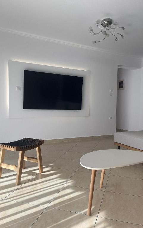 a living room with two tables and a tv on a wall at Pnoe Home in Kavála