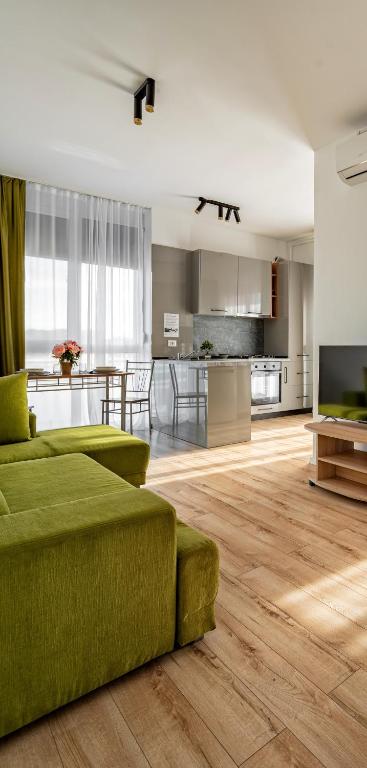 a living room with a green couch and a kitchen at Sika Buzz Premium Apartment - cazare Arad - self check-in in Arad
