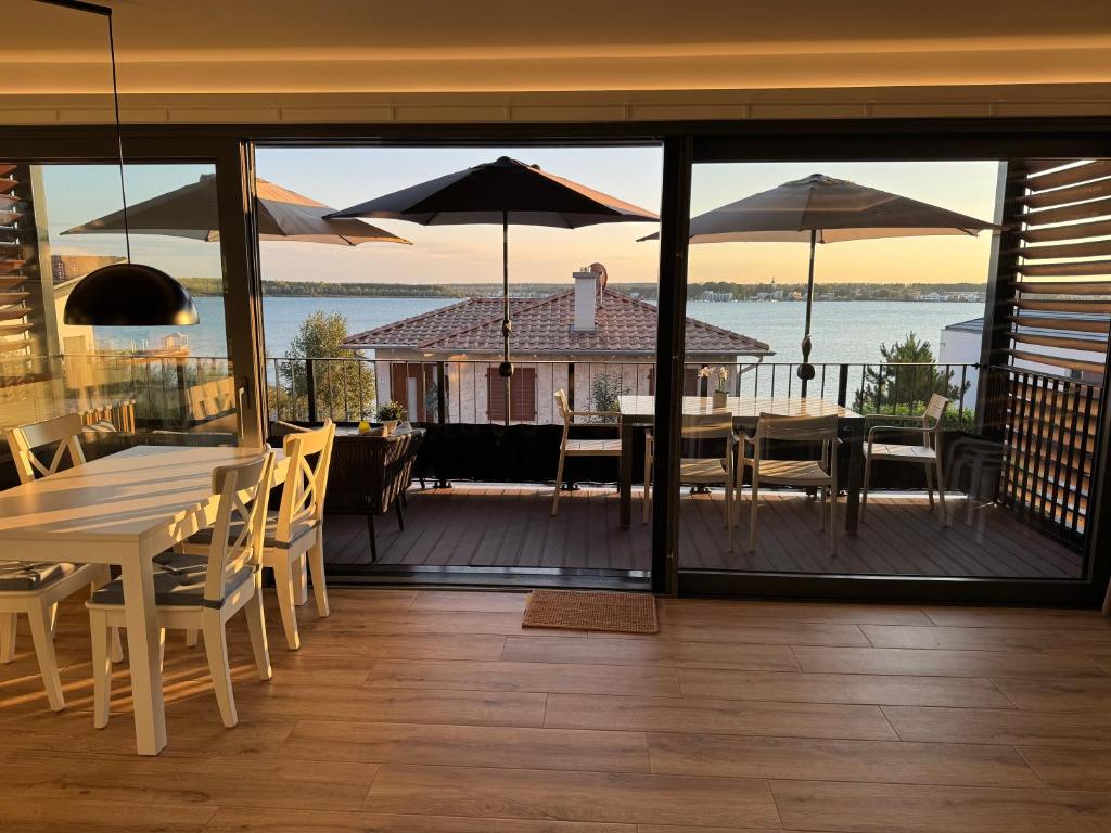 a dining room with tables and umbrellas on a deck at Fewo Wellenklang Hainer See bei Leipzig in Neukieritzsch