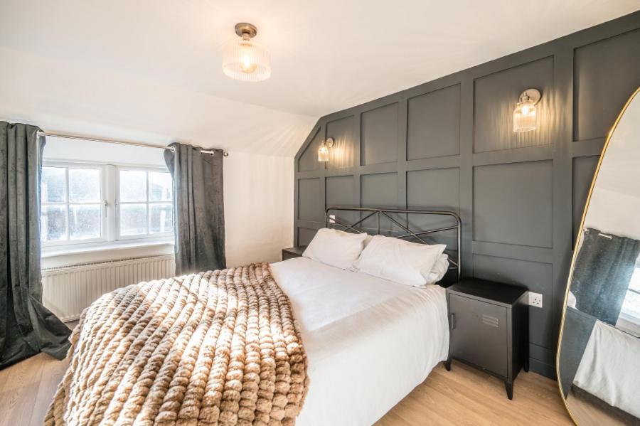 een slaapkamer met een groot bed en een spiegel bij Pink Cottage in Leiston