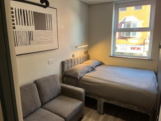 a bedroom with a bed and a couch and a window at The Stadium Hotel Anfield in Liverpool