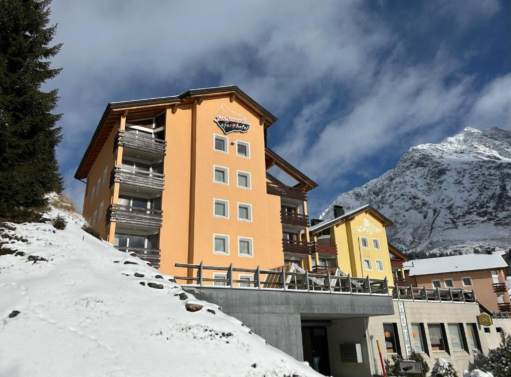 a building in the snow with a mountain in the background at Hotel-Aparthotel San Bernardino in San Bernardino