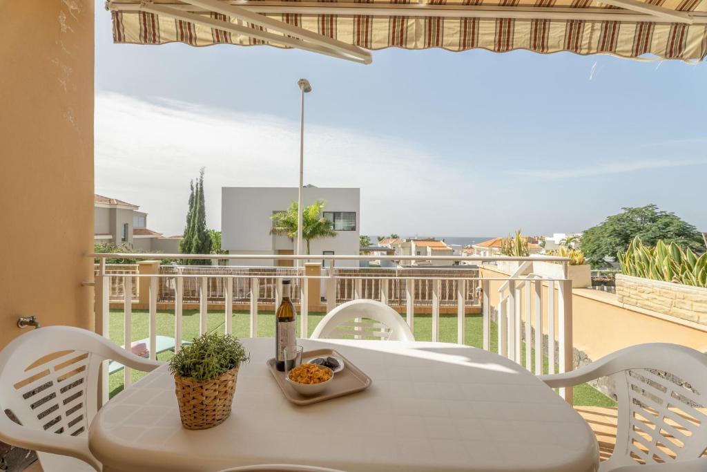 una mesa blanca con una botella de vino en el balcón en Brisas Chasna 2, en Adeje