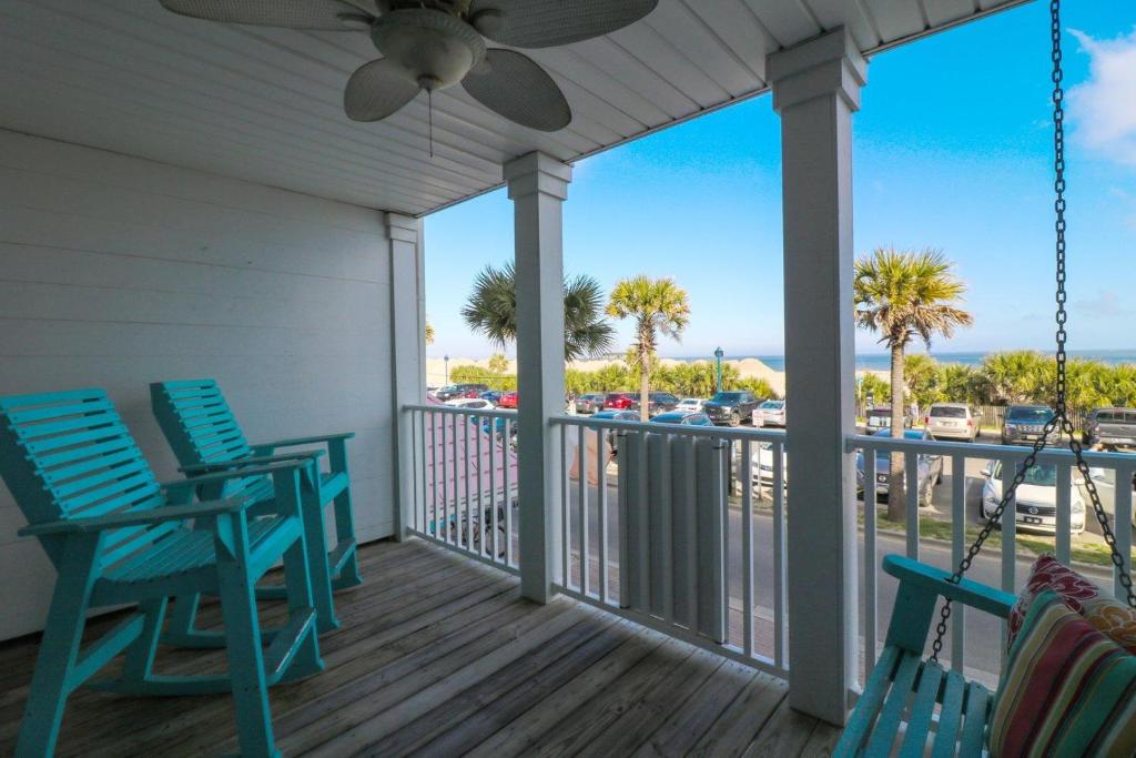 a porch with blue chairs and a balcony with palm trees at Atlantic Sunrise in Tybee Island
