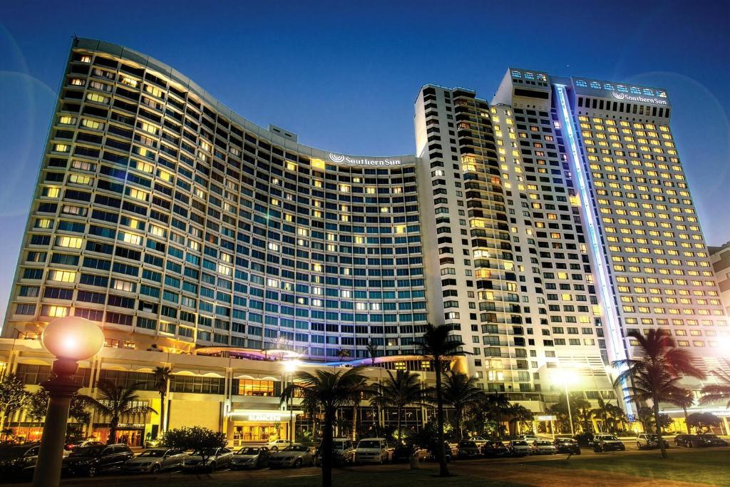 Un gran edificio con coches aparcados delante. en Southern Sun Elangeni & Maharani, en Durban