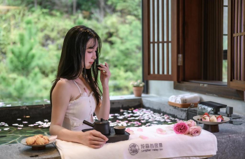 een vrouw die op een mobiele telefoon praat naast een tafel met bloemen bij LongSen Valley Inn in Zhukeng