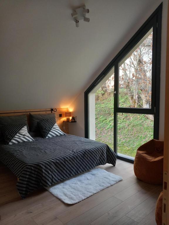 een slaapkamer met een bed en een groot raam bij Les grands Combes in Saint-Léger-les-Mélèzes