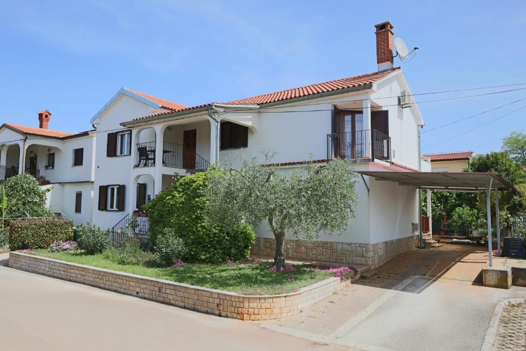 een wit huis met een boom ervoor bij Apartment Luciana in Umag