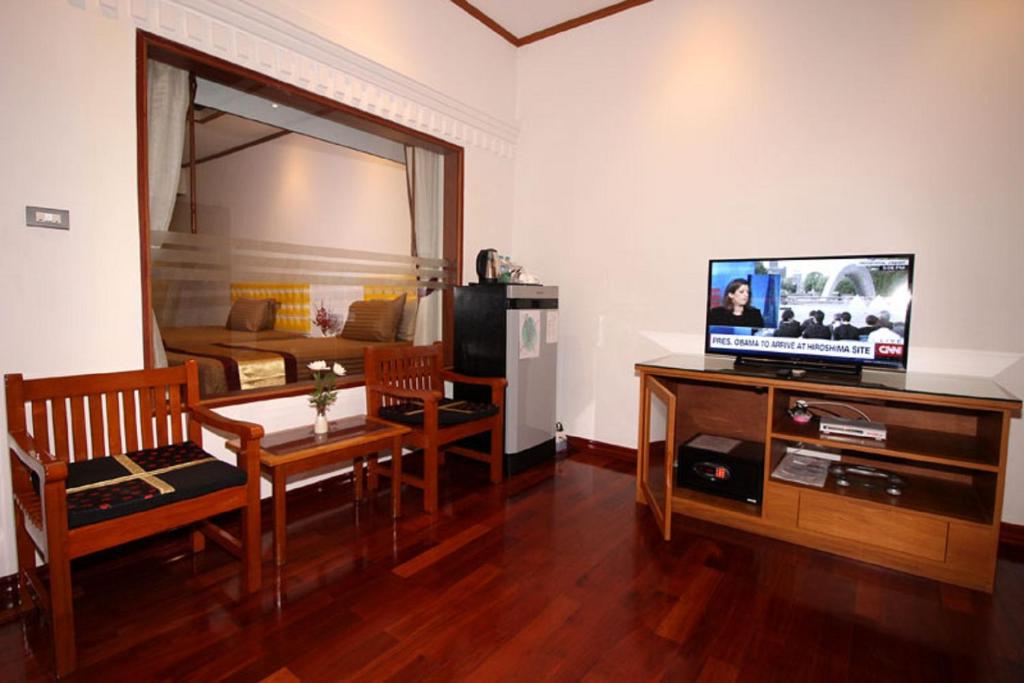 un soggiorno con TV, tavolo e sedie di Myanmar Life Hotel a Yangon