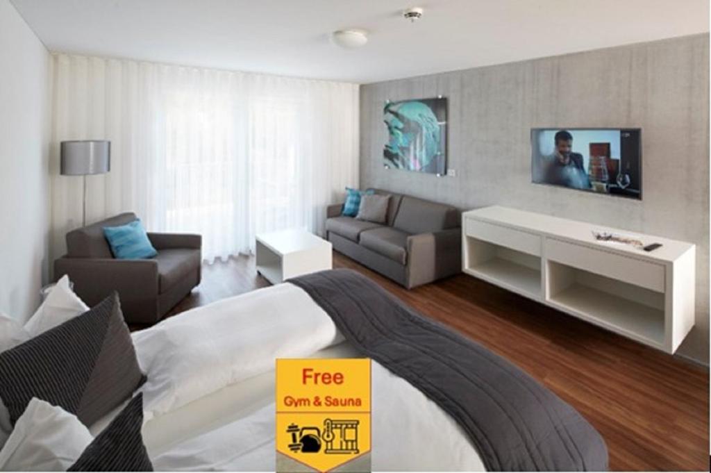 Una habitación de hotel con una cama, un sofá y un televisor. en Aparthotel Baden, en Baden