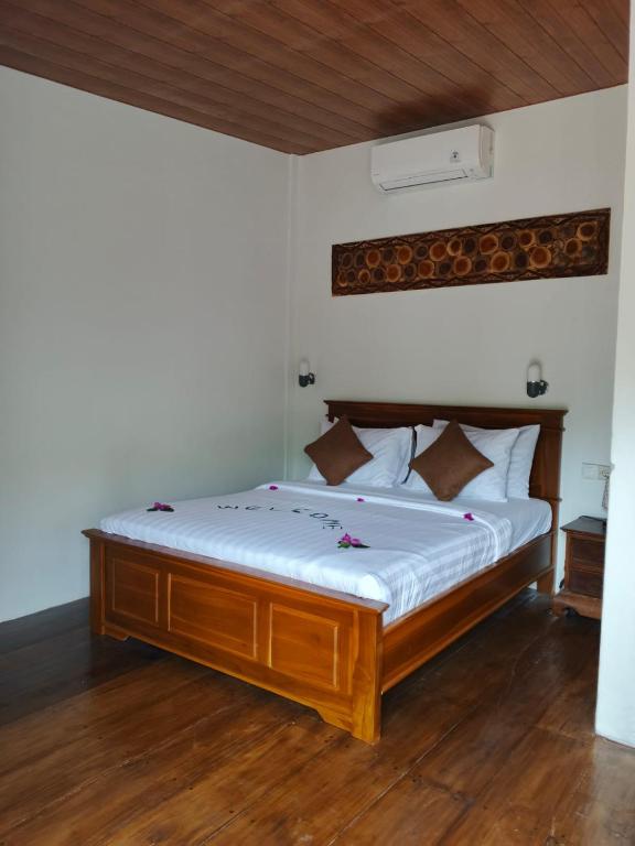 a bedroom with a wooden bed with white sheets at Jay Guest House Gili Gede in Sekotong