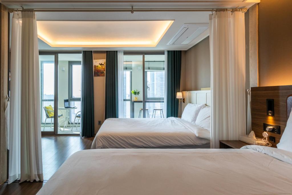 una camera d'albergo con due letti e un balcone di Bona Haeundae fantastic ocean view #Sea and Haeundae Gunam-ro# a Busan