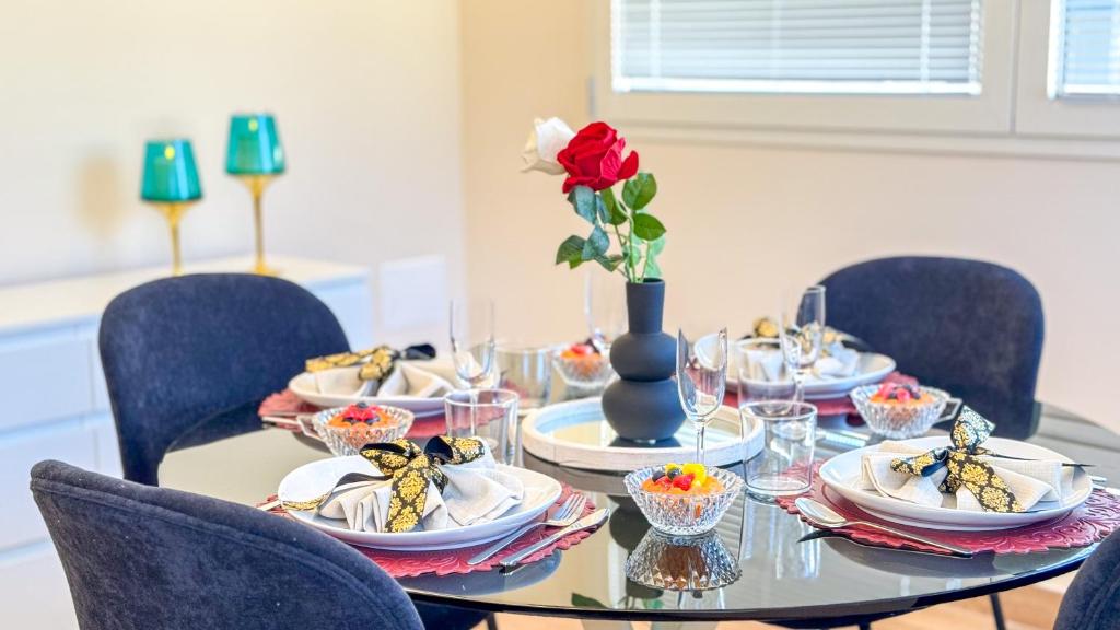 a table with plates and a red rose in a vase at Bon Bon Suite by Ca-sa Check in Sottomarina