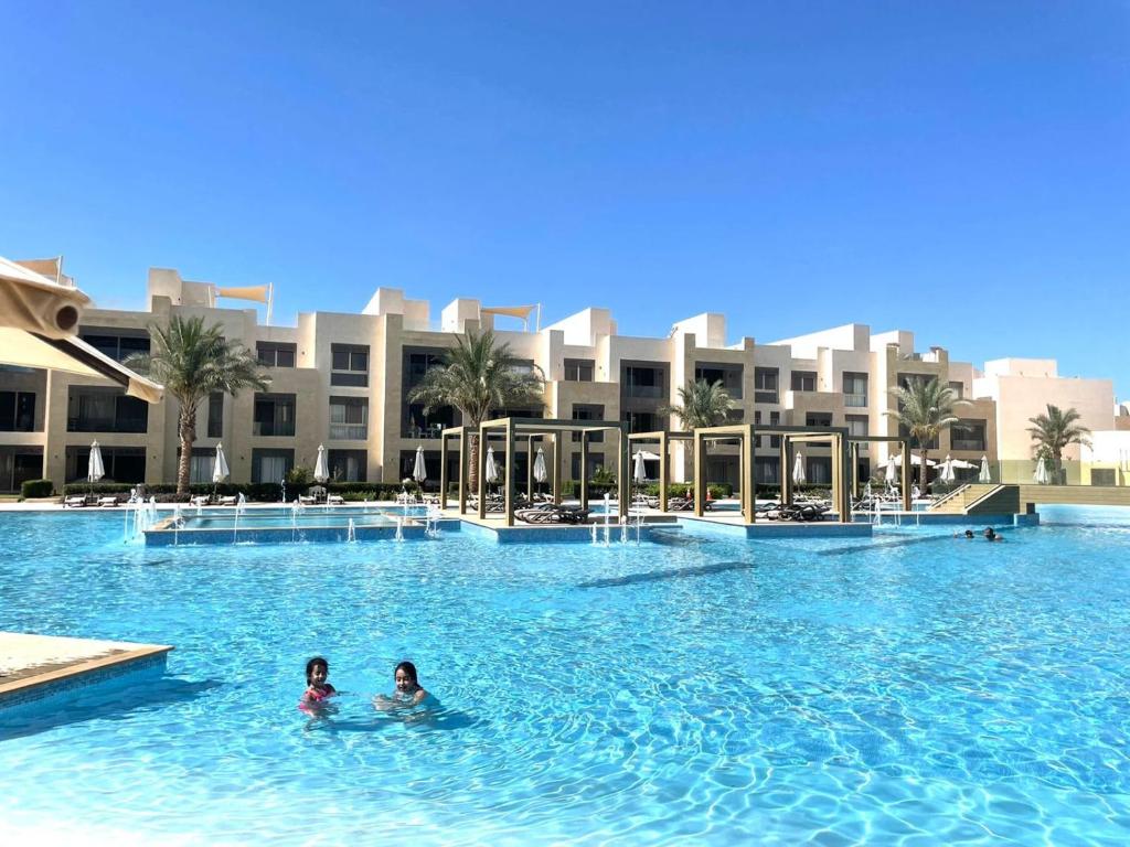 due persone che nuotano in una piscina in un resort di Mangrove M1-5B-13 a Banī Ghālib