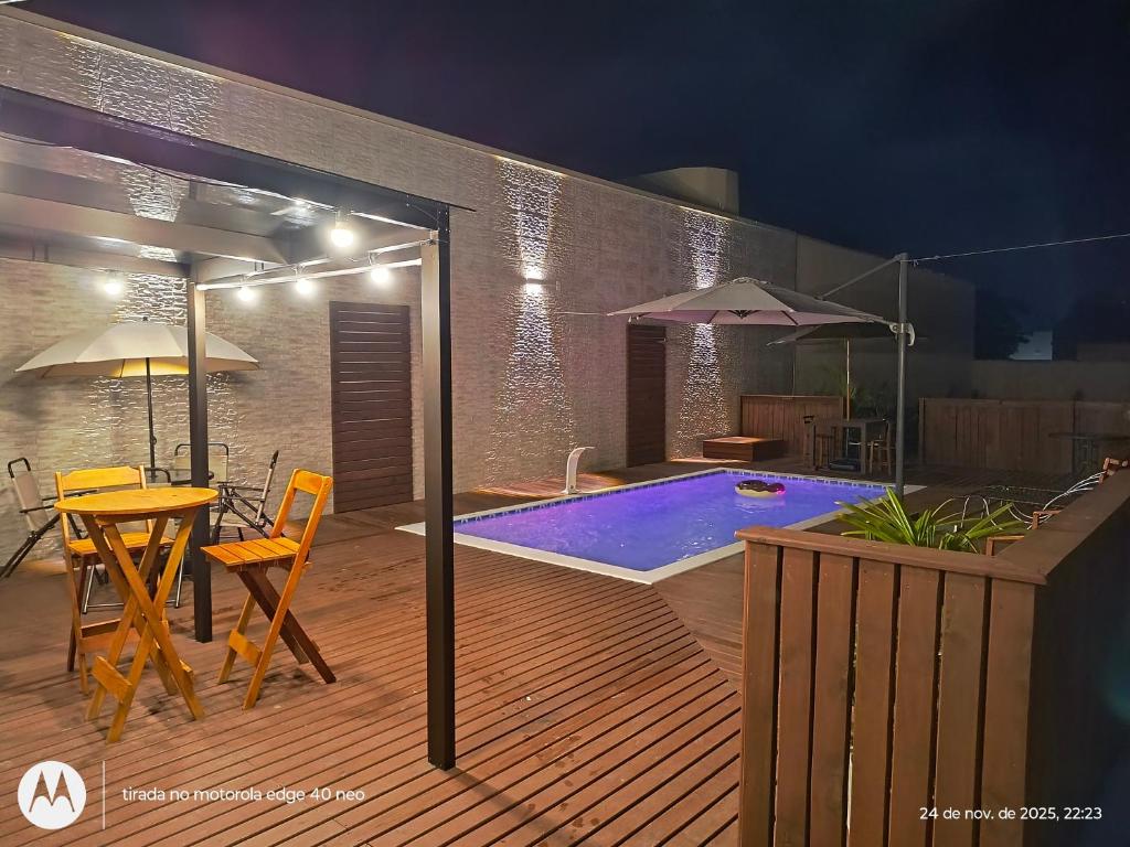 a deck with a swimming pool and a table and chairs at Acomodação Cambirela in Palhoça