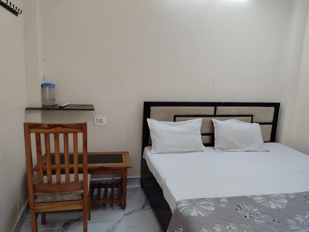een slaapkamer met 2 bedden, een stoel en een tafel bij Maa tulsi guest house in Ayodhya