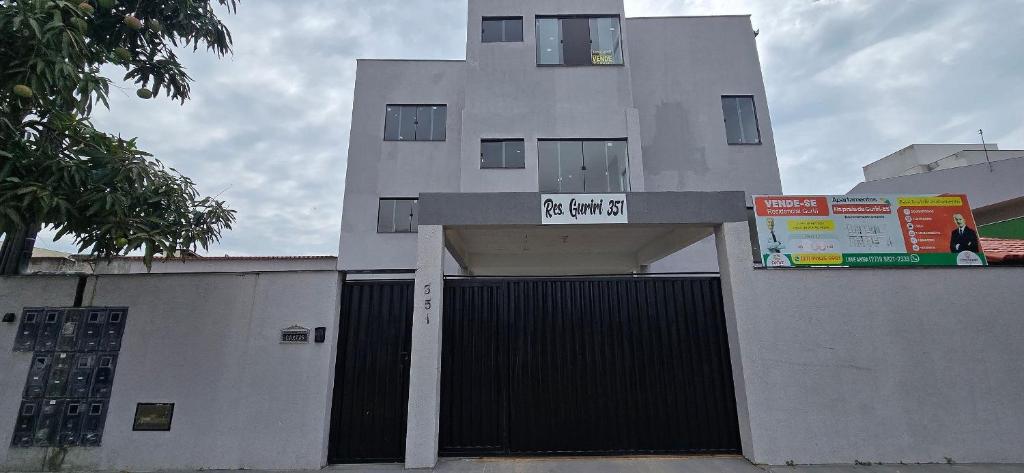 a white building with a gate with a sign on it at Apartamento Barra Vento 2 in Guriri