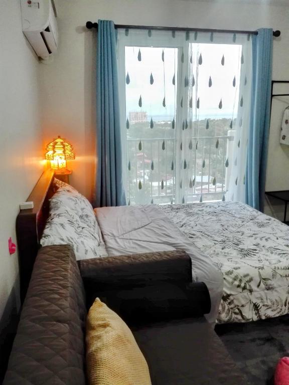 a bed with a couch in front of a window at Oshanbyu Transient Home in Basbas
