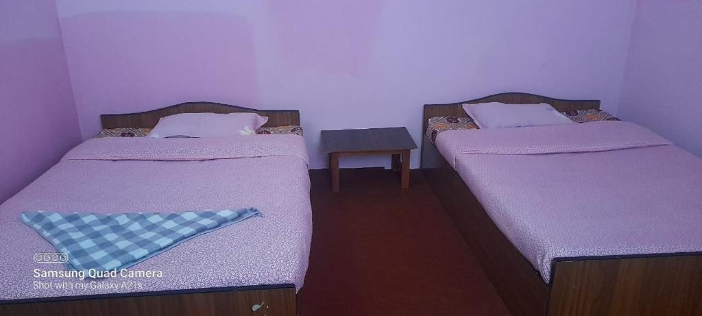 two twin beds in a room with a table at Saura Point Homestay in Nagarkot