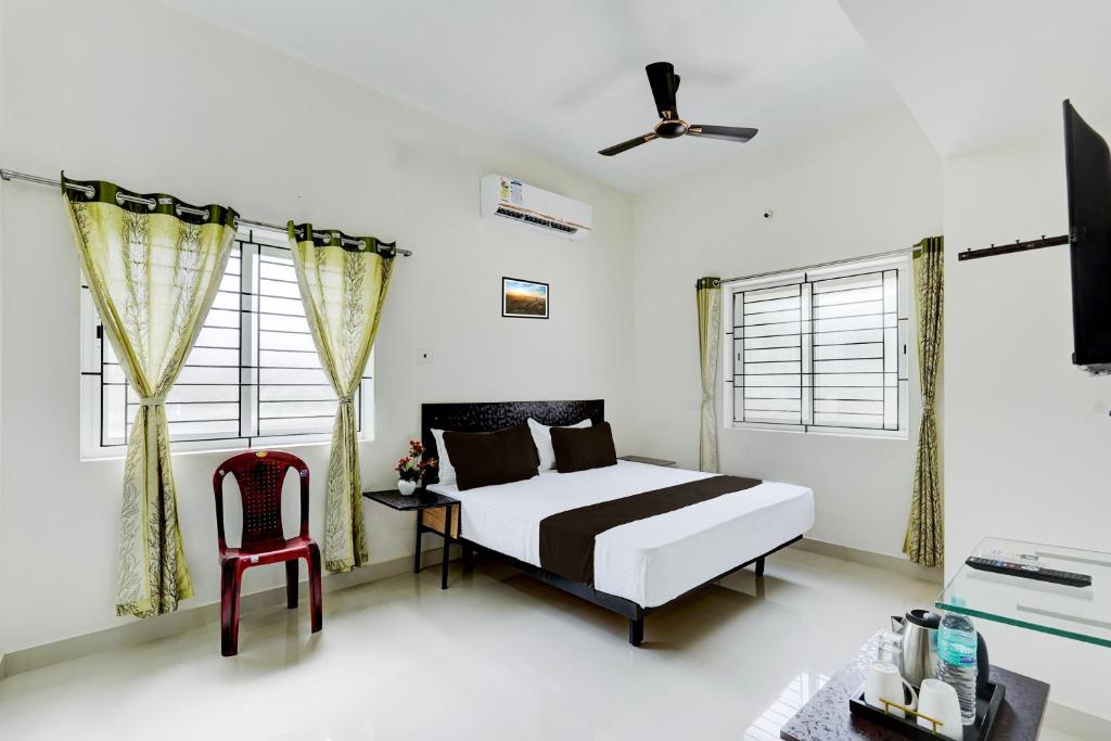 um quarto com uma cama e uma cadeira vermelha em Hotel O Elegant Residency Vandalur Zoo em Chennai