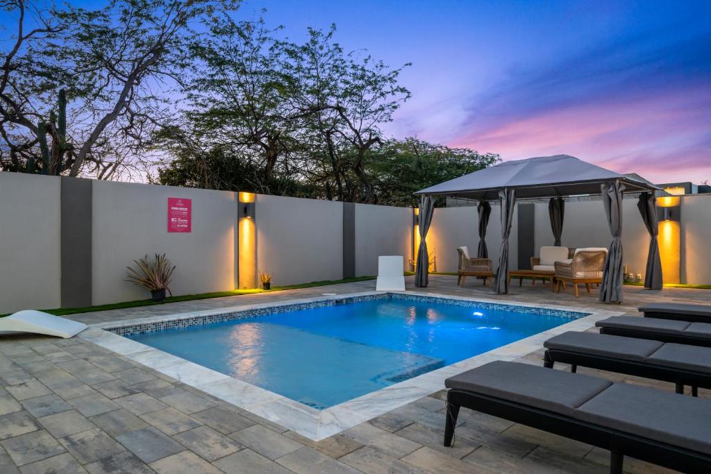 einen Pool mit Pavillon neben einem Gebäude in der Unterkunft Monserat 33Q in Palm-Eagle Beach