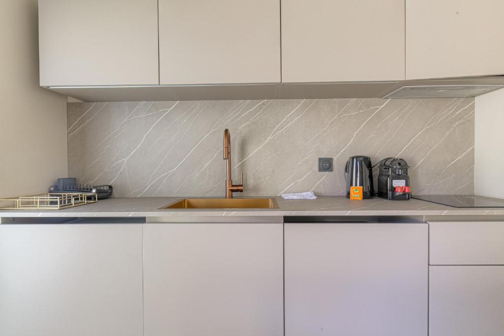 a kitchen with white cabinets and a sink at Résidence moderne avec appartements lumineux et rénovés aux portes de Lyon in Écully